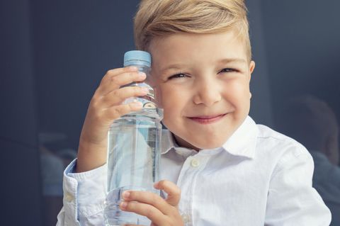 Ein Junge hält seine Trinkflasche und grinst