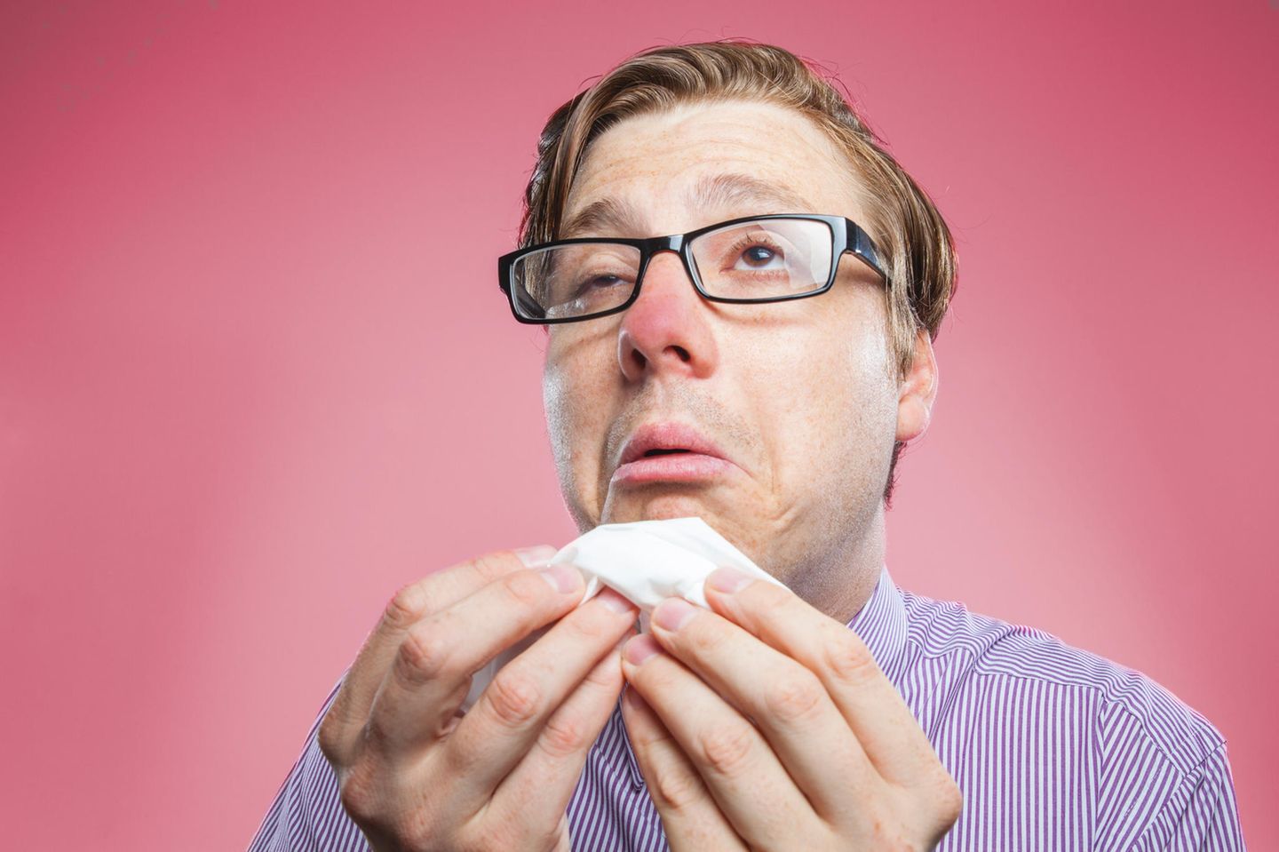Ein erkälteter Mann putzt sich die Nase.