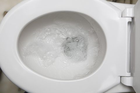 Eine Toilettenschüssel von oben, in der gerade die Spülung betätigt wurde. Durch die Klobrille hindurch sieht man Wasserwirbel
