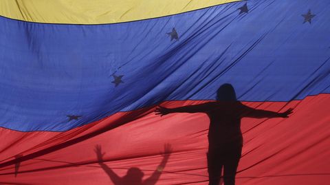Protestanten hinter einer Flagge von Venezuela