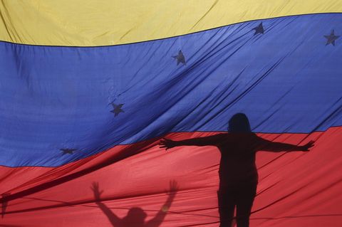 Protestanten hinter einer Flagge von Venezuela