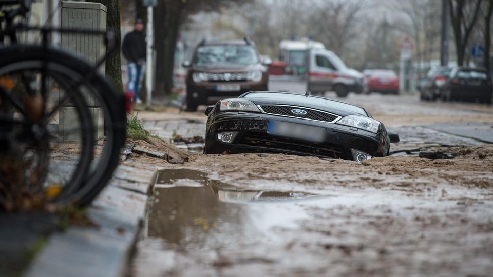 Nach dem Wasserrohrbruch ist die Straße abgesackt und hat ein Auto zur Hälfte in die Tiefe gerissen Nach dem Wasserrohrbruch ist die Straße abgesackt und hat ein Auto zur Hälfte in die Tiefe gerissen