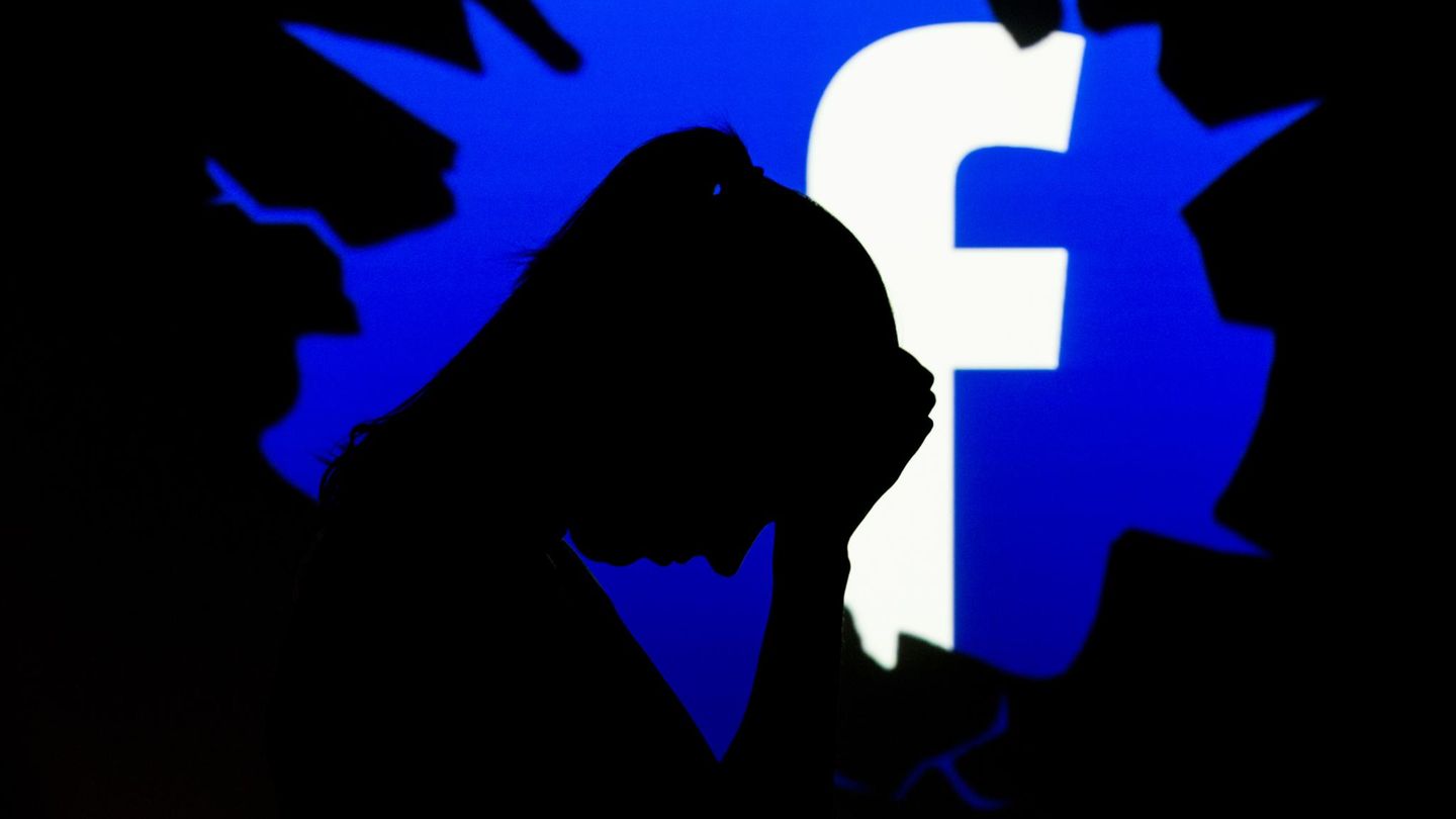 Der Schattenriss einer besorgten Frau ist vor dem Facebook-Logo zu sehen