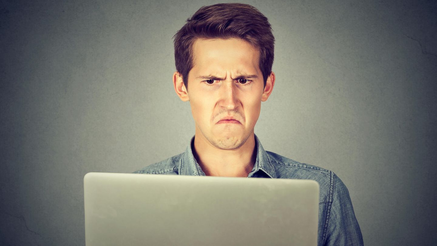 Ein Mann schaut irritiert auf seinen Laptop-Bildschirm
