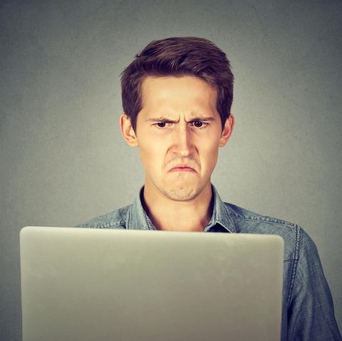 Ein Mann schaut irritiert auf seinen Laptop-Bildschirm