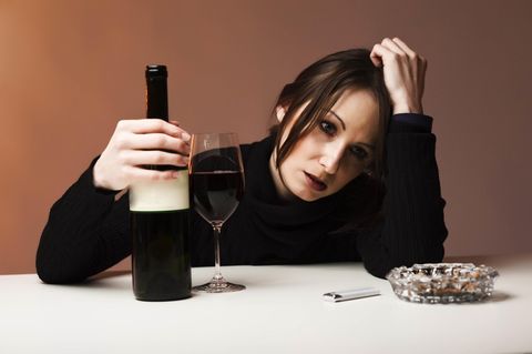 Eine traurige Frau trinkt Wein, während sie traurige Musik hört