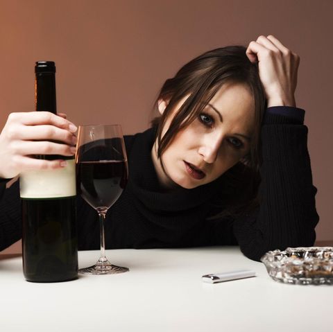 Eine traurige Frau trinkt Wein, während sie traurige Musik hört