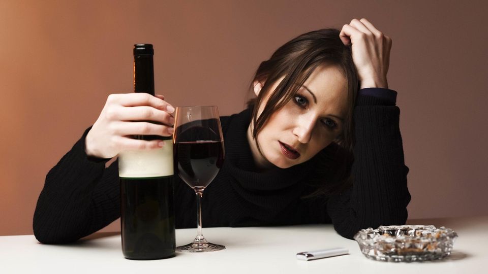Eine traurige Frau trinkt Wein, während sie traurige Musik hört