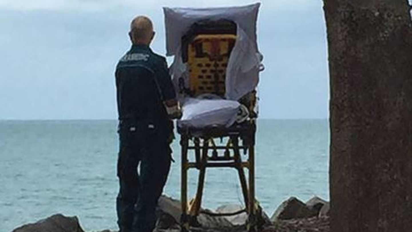 Ein letzter Blick aufs Meer: Ein Mitarbeiter des Queensland Ambulance Service mit der Patientin