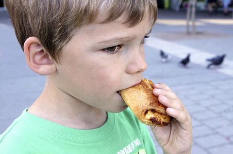 Ein kleiner Junge isst ein Gebäckstück
