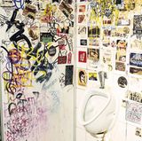 Eine öffentliche Männertoilette beklebt mit Aufklebern