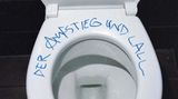 Eine Toilettenbrille mit den Worten "Der Aufstieg und Lall"