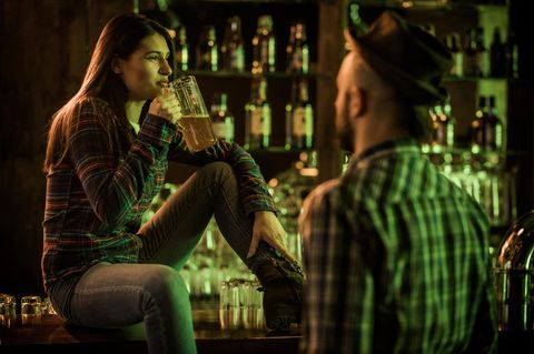 Eine Frau trinkt nachdenklich ein Bier in einer Bar