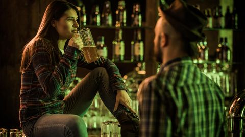 Eine Frau trinkt nachdenklich ein Bier in einer Bar