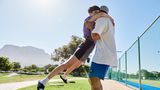 Neben einem Tennisplatz liegt sich das Paar Fani und Anees in den Armen