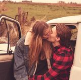 Ein verliebtes Paar sitzt knutschend auf dem Fahrersitz eines alten französischen Lieferwagens