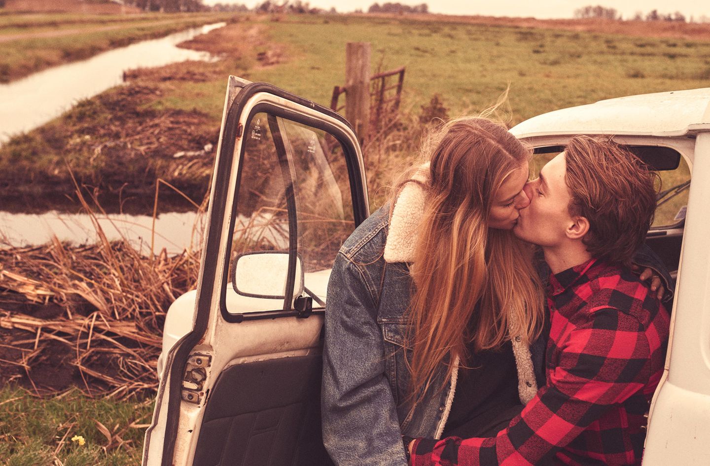 Ein verliebtes Paar sitzt knutschend auf dem Fahrersitz eines alten französischen Lieferwagens