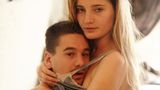 Das junge Paar, Emma und Sam, sitzt auf der Kante ihres Bettes und umarmt sich