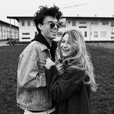 Mitten auf der Wiese inmitten eines Studentenwohnheims liegt sich ein Paar in den Armen