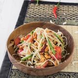 Som Tam – grüne-Papaya-Salat aus Thailand      Zutaten:    500 g grüne Papaya (aus dem Asia-Laden), 5 EL Erdnüsse, 3 große Knoblauchzehen, 3–4 Thai-Chili-Schoten (nach Belieben mehr), 3 EL getrocknete kleine Shrimps (aus dem AsiaLaden), 100 g Schlangenbohnen, Salz, 150 g Cocktailtomaten, 4 EL Fischsauce, plus mehr zum Abschmecken, 2 EL Limettensaft, plus mehr zum Abschmecken, 2 EL Palmzucker, plus mehr zum Abschmecken      Zubereitung:    Klassisch werden alle Zutaten für den Papaya-Salat in einem sehr großen Mörser miteinander vermischt.  Wer keinen sehr großen Mörser hat, stampft am besten die kleinen Zutaten miteinander und mischt die Masse anschließend in einer Schüssel mit den Papaya-Raspeln.        Die Papaya schälen, Fäden und Kügelchen in der Mitte entfernen und das Fruchtfleisch in lange dünne Streifen raspeln. Die Erdnüsse in einer Pfanne ohne Fett rösten, bis sie Farbe annehmen und beiseitestellen. Den Knoblauch abziehen und fein hacken. Die Chilischoten waschen, abtupfen und mit dem Knoblauch in einem großen Mörser zerreiben. Die getrockneten Shrimps zugeben und mit dem Stößel grob zerkleinern. Die Schlangenbohnen putzen, in mundgerechte Stücke schneiden und in Salzwasser etwa 3 Minuten blanchieren. Abgießen und mit der Hälfte der Erdnüsse im Mörser verarbeiten, die Bohnen aber nur leicht zerdrücken.        Die Cocktailtomaten waschen, trockentupfen, halbieren und im Mörser leicht zerdrücken, bis Saft austritt.        Alles in eine Schüssel umfüllen, mit Fischsauce, Limettensaft und Palmzucker würzen und alles vermischen. Vorsichtig die Papaya-Raspeln untermischen. Bei Bedarf nochmals mit Fischsauce, Palmzucker oder Limettensaft nachwürzen und mit den restlichen Erdnüssen anrichten.