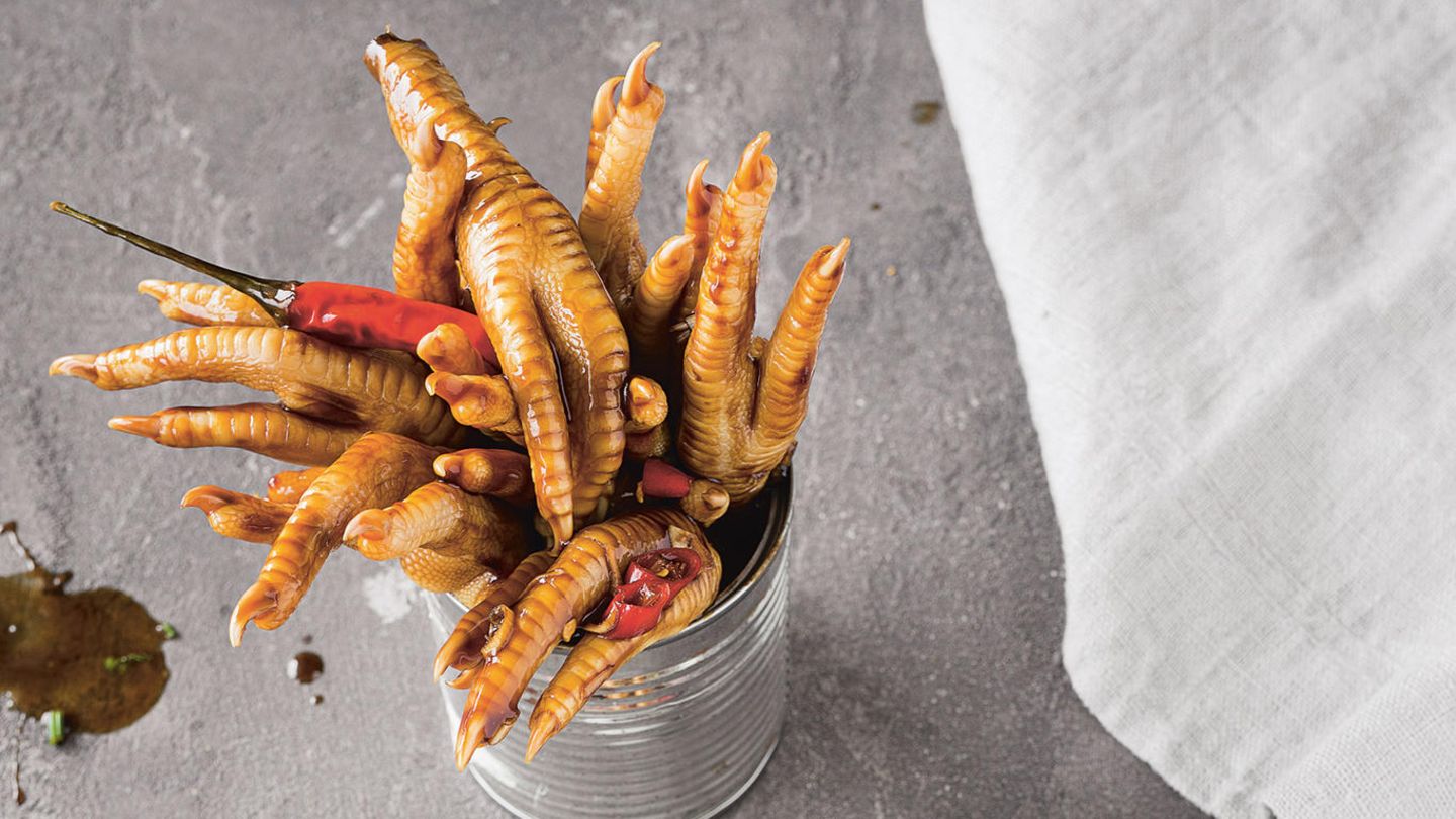 Scharfe Hühnerfüsse mit Sojasauce und Paprika      Zutaten:    3 Stangen Zitronengras,7 kleine Chilischoten, 3 Kafir-Limettenblätter, 200 ml helle Sojasauce, Salz, 2 kg Hühnerfüße, 2 rote Paprikaschoten, 3 Stangen Sellerie, 4 Frühlingszwiebeln, 4 Knoblauchzehen, 3 EL Sonnenblumenöl, 2 Sternanis, 450 ml Sojasauce, 50 ml Sesamöl, 5 EL Speisestärke, 1/4 Bund Koriander      Zubereitung:    Für die Hühnerfüße das Zitronengras und die Chilischoten waschen. Das Zitronengras und eine Chilischote etwas andrücken. In einem großen Topf 500 ml Wasser mit Zitronengras, Kafir-Limettenblättern, der Chilischote, der hellen Sojasauce und 1 TL Salz zum Kochen bringen. Die Hühnerfüße im Sud bei niedriger Temperatur 1 Stunde köcheln lassen.         Währenddessen die Paprika waschen, trockentupfen, von Stielansätzen und Samen befreien und in mundgerechte Streifen schneiden. Den Sellerie putzen und in 0,5 cm lange Stücke schneiden, die Frühlingszwiebeln putzen und in Ringe schneiden. Den Knoblauch abziehen und grob hacken.         Die weich gekochten Hühnerfüße abgießen und die Krallen mit einem kleinen Messer abschneiden.         In einer großen Pfanne oder einem Wok das Sonnenblumenöl bei hoher Temperatur erhitzen. Paprika, Sellerie und Knoblauch darin anbraten. Sternanis, Frühlingszwiebeln und die übrigen Chilischoten dazugeben. Sojasauce, Sesamöl und etwas Wasser zugeben und alles zum Kochen bringen, dann die Temperatur reduzieren.         Die Speisestärke in etwa 150 ml Wasser verrühren. Die Mischung nach und nach in den köchelnden Pfanneninhalt träufeln und alles andicken lassen. Die Sauce ist sämig genug, wenn sie die Konsistenz von flüssigem Honig hat.         Die Hühnerfüße in die Sauce geben. Den Koriander waschen, trockenschütteln und grob hacken, kurz vor dem Servieren ebenfalls unterrühren. Im Wok oder in tiefen Tellern reichen.