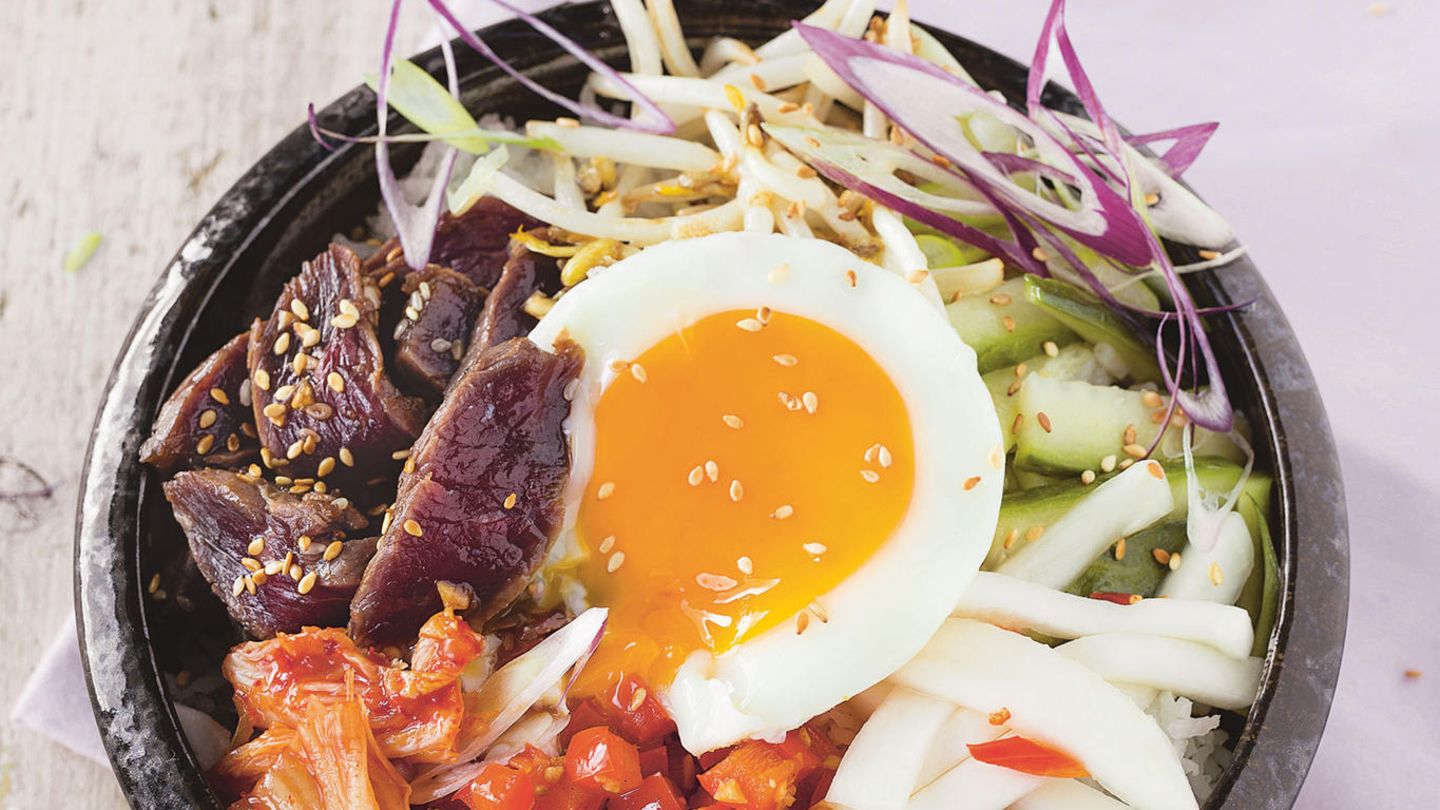 Bibimbap: koreanische Bowl        Zutaten:    Für das Fleisch und die Marinade: 2 Knoblauchzehen, 3 EL Sojasauce, 1 EL Honig, 1 EL Sesamöl, 1 TL Sesamsaat, 250 g Lendensteak vom Rind,     Für das Gemüse: 1/3 Salatgurke, 1 TL Sesamöl, 2 EL Reisessig, Salz, 2 Mairübchen oder 1/2 weißer Rettich, 1 Chilischote, gehackt, 2 EL Weißweinessig, 1 EL Sonnenblumenöl Für den Kimchi: 200 g Chinakohl, Salz, 1 TL brauner Zucker, 1 EL Sojasauce, 1 EL Chilipaste,     Außerdem: 250 g Basmati-Reis, 1 rote Paprikaschote, 1 Knoblauchzehe, 1 Frühlingszwiebel, 3 EL Sonnenblumenöl, Salz, 2 Handvoll Sojasprossen, 4 Eier        Zubereitung:    Für die Rindfleisch-Marinade die Knoblauchzehen abziehen und hacken. Mit Sojasauce, Honig, Sesamöl sowie Sesamsaat vermengen und das Rindfleisch in einem Plastikbeutel oder einer Schüssel über Nacht darin marinieren.    Für das Gemüse die Gurke waschen und in mundgerechte Stücke schneiden. Mit Sesamöl, Reisessig und 1/2 TL Salz über Nacht marinieren. Die Mairübchen schälen und in dicke Stifte schneiden. Mit Chili, 1/2 TL Salz, Weißweinessig und Sonnenblumenöl mischen, über Nacht marinieren. Für den schnellen Kimchi den Chinakohl putzen und mundgerecht schneiden. Mit 1 EL Salz, dem braunen Zucker, Sojasauce und Chilipaste gut durchkneten. Mindestens über Nacht durchziehen lassen.    Am Zubereitungstag den Reis mit der doppelten Menge Wasser bissfest garen. Währenddessen die Paprika waschen, abtupfen, von Stielsatz sowie Samen befreien und würfeln, den Knoblauch abziehen und hacken, die Frühlingszwiebel putzen und dünn schneiden.    In einer Pfanne 1 EL Öl erhitzen. Paprika und Knoblauch darin kurz scharf anbraten, salzen und warm stellen.    Anschließend die Sojasprossen scharf anbraten, salzen und ebenfalls warm stellen.  Das Fleisch aus der Marinade nehmen, auf jeder Seite scharf anbraten und aufschneiden. In einer zweiten Pfanne im übrigen Öl die Spiegeleier braten. Alles miteinander anrichten. 