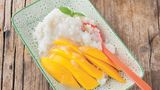 Sticky Rice mit Mango      Zutaten:    200 g Milchreis (alternativ ein anderer Rundkornreis), Salz, 2 Dosen Kokoscreme (800 ml), 60 g Zucker, 1 TL Speisestärke, 2 reife Thai-Mangos, 8–12 Blätter Thai-Basilikum      Zubereitung:    Den Reis unter fließendem kaltem Wasser waschen. Mit der dreifachen Menge Wasser und einer Prise Salz in einem Topf oder Reiskocher zum Kochen bringen, den Deckel auflegen und auf geringster Temperatur gar quellen lassen.        Währenddessen die feste Kokoscreme (die Milch darunter kann für andere Zubereitungen verwendet werden) in einem kleinen Topf mit dem Zucker und etwas Salz bei geringer Temperatur erwärmen. Von der warmen Kokoscreme 2 /3 unter den noch warmen Reis rühren.        Die Speisestärke in 3 EL kaltem Wasser auflösen und unter die übrige Kokoscreme rühren, einmal auf - kochen und andicken lassen. Die Mangos schälen und das Fruchtfleisch vom Kern schneiden, in Spalten schneiden. Thai-Basilikum waschen und trockenschütteln.        Zum Anrichten die Mango auf dem Reis anrichten, mit Kokossauce beträufeln und mit Thai-BasilikumBlättchen dekoriert servieren.