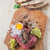 Beef Tatar      Zutaten:    600 g Rinderschulter, 2 Schalotten, 8 Essiggurken, 1 EL Worcester-Sauce, Fleur de Sel, frisch gemahlener schwarzer Pfeffer, 4 Eigelb, 2 EL Kapern aus dem Glas, 2 EL grober Senf,    Außerdem: glatte Petersilie für die Dekoration, frisches Bauernbrot      Zubereitung:  Für das Tatar das frische Fleisch sofort zubereiten und unverzüglich verzehren. Von Silberhäuten, Sehnen und Fett befreien. Zunächst in dünne Scheiben, dann in Streifen und feine Würfel schneiden und zum Schluss hacken.        Die Schalotten abziehen und fein würfeln. Die Hälfte der Gurken ebenfalls fein würfeln und die anderen Gurken dünn auffächern.        Zum Servieren aus dem Fleisch entweder einen großen oder vier kleine, gleich große Laibe formen und auf einem Holzbrett platzieren. Mit Worcester-Sauce beträufeln und mit Salz und Pfeffer würzen. Eigelb (Serviervorschlag: in halben Eierschalen), Zwiebelwürfel, Gurkenwürfel, Gurkenfächer, Kapern und Senf dazu anrichten. Die Petersilie waschen, trockenschütteln, die Blätter abzupfen und das Brett damit dekorieren.    Dazu passt frisches Bauernbrot.