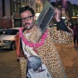 Merkmale des ultimativen Hipsters: ein Mantel, so hässlich, dass er schon fast wieder cool ist und ein Audiowiedergabegerät (das MacBook ist natürlich voll ironisch gemeint, weil Kapitalismus und so), mit dem sonst niemand auf der Straße zu sehen ist. So individuell!