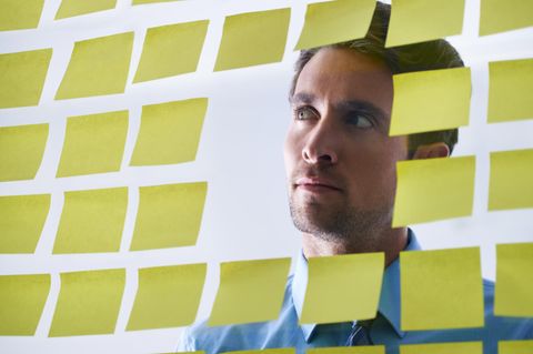 Ein Mann blickt durch ein Fenster, das voller Post-its klebt