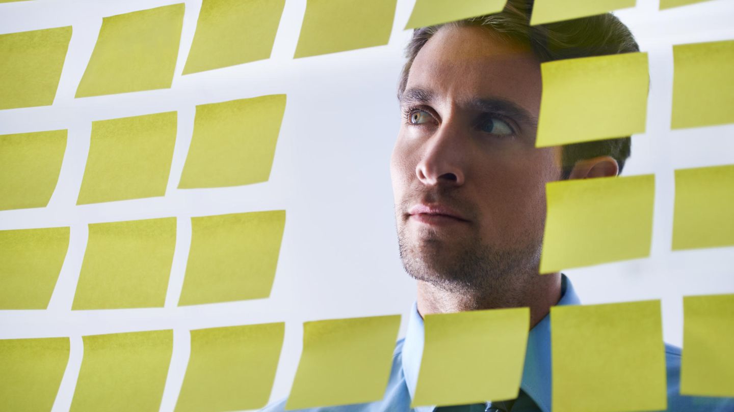 Ein Mann blickt durch ein Fenster, das voller Post-its klebt
