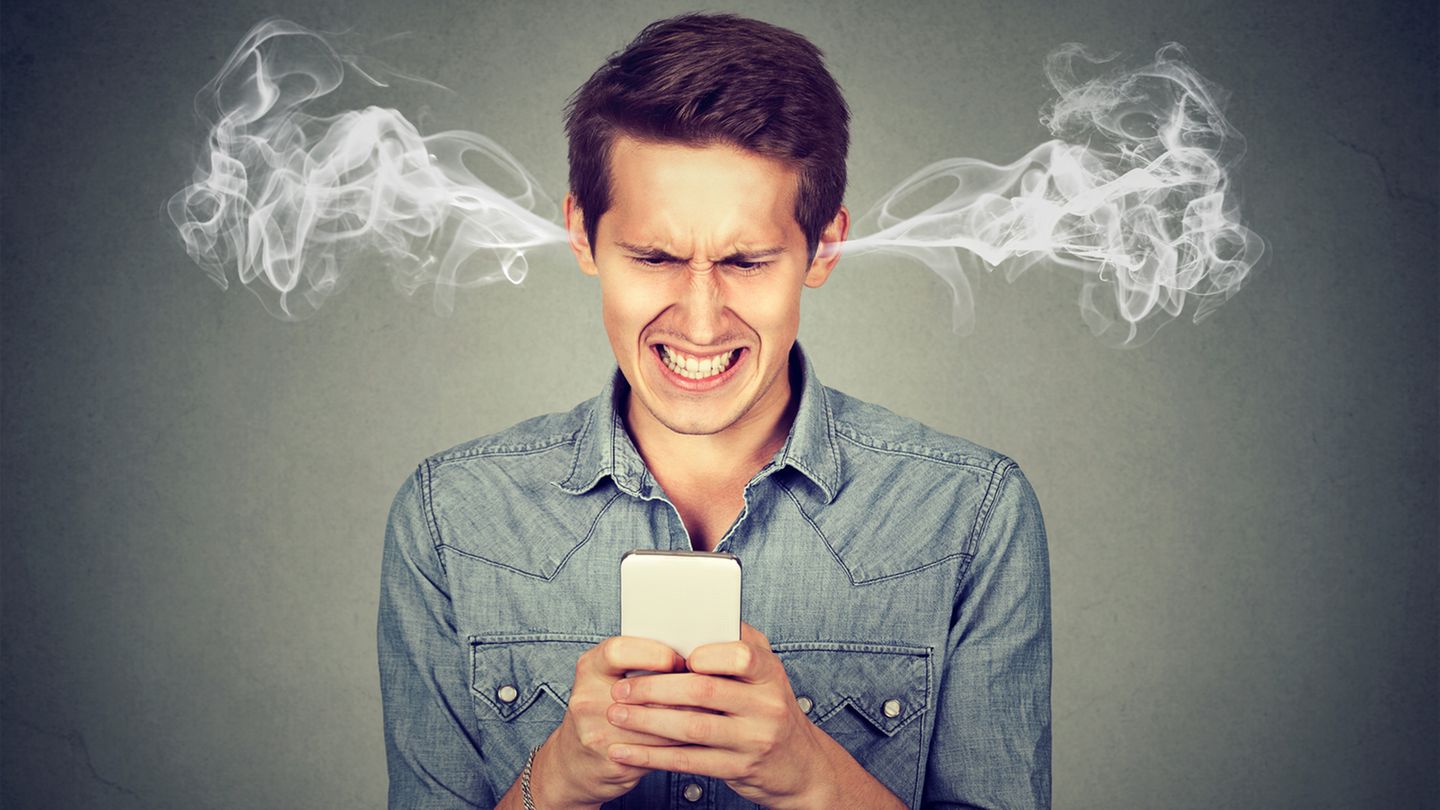 Einem Mann mit Smartphone kommt vor Wut Rauch aus den Ohren