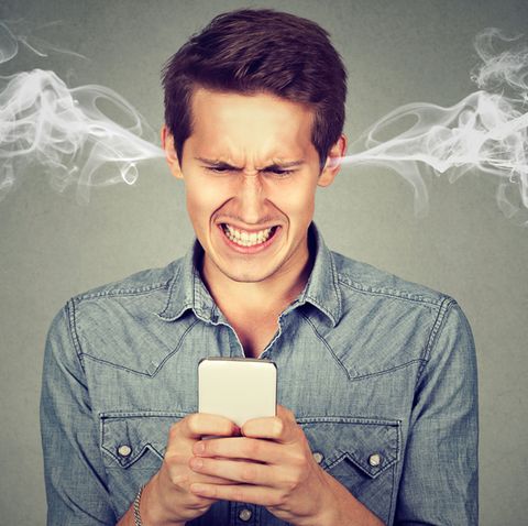 Einem Mann mit Smartphone kommt vor Wut Rauch aus den Ohren