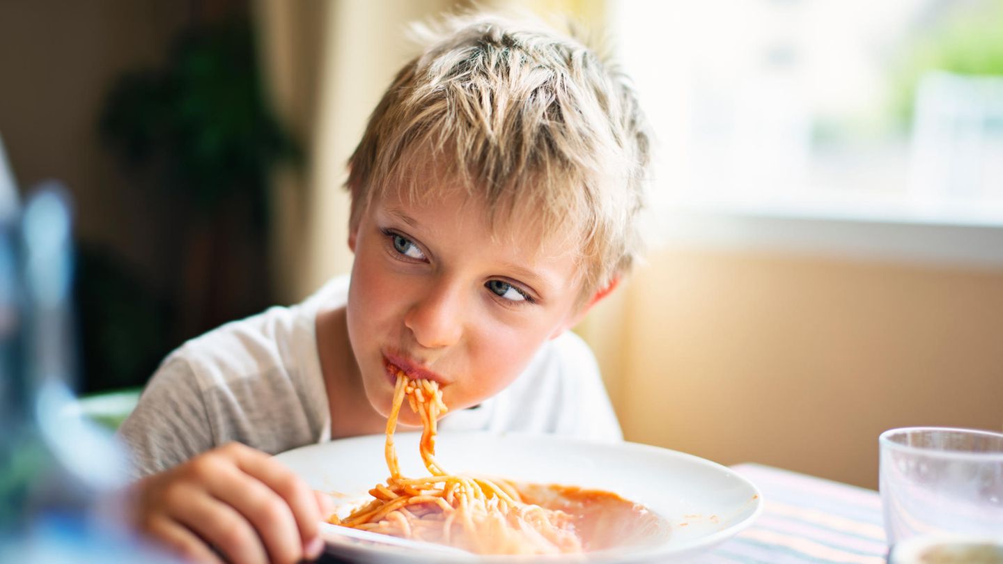 Ein Junge isst Spaghetti und grinst