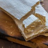 Spanien: Turrón  Was den Deutschen ihr Buttergebäck, ist den Spaniern ihr Turrón. In der Vorweihnachtszeit stapelt sich die klebrige Leckerei landesweit in den Ladentheken. Die Delikatesse wird aus Mandeln, Zucker, Honig und Ei hergestellt und erinnert in der Konsistenz an klebriges Konfekt. Die Spanier gehen mit dem Trend: Mittlerweile gibt es zuckerfreie Varianten und sogar veganes Turrón.