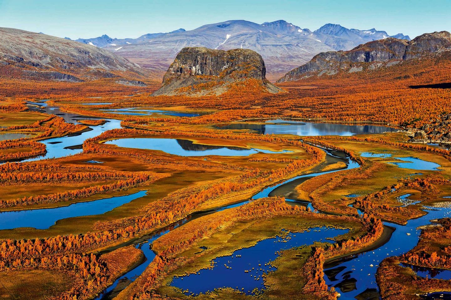 Herbst in Schwedisch-Lappland: Das Flussdelta des Rapaälven mit seinen weit verzweigten Flussläufen erstrahlt in bunten Farben, im Bildzentrum der markante Felsklotz Nammatj. Die Berge im Hintergrund gehören bereits zum Nationalpark Sarek.
