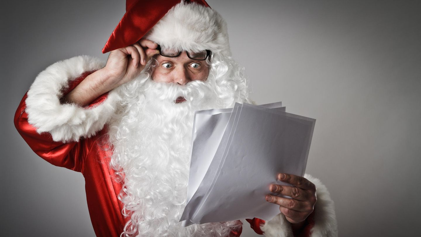 Ein Weihnachtsmann guckt verwundert auf einen Wunschzettel