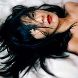 Eine asiatische Frau liegt auf einem Bett