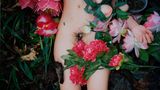 Der nackte Unterleib einer Frau zwischen Blumen