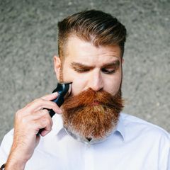 Mann trimmt sich rotfarbenden Vollbart