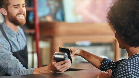Eine Frau zahlt in einem Laden mit dem Smartphone