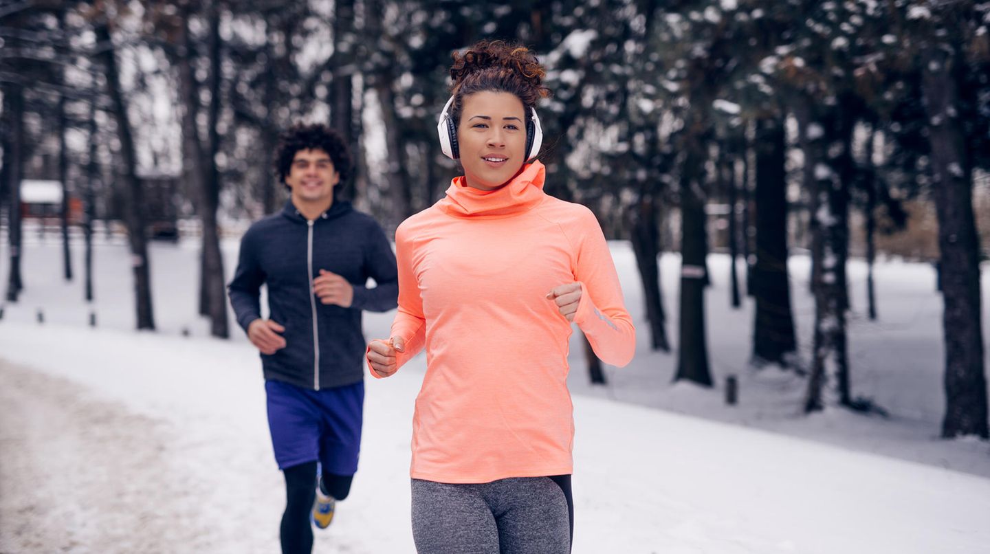 Joggen im Winter: Eine Frau und ein Mann laufen auf einem verschneiten Weg