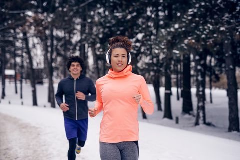 Joggen im Winter: Eine Frau und ein Mann laufen auf einem verschneiten Weg