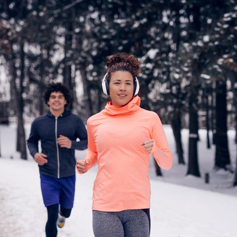 Joggen im Winter: Eine Frau und ein Mann laufen auf einem verschneiten Weg