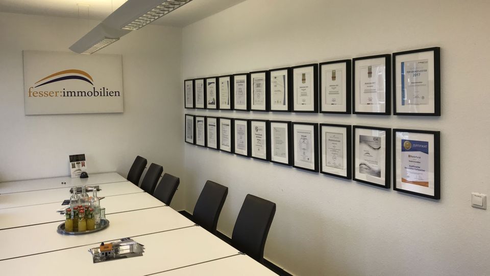 Besprechungsraum bei "fesser immobilien": An der Wand hängen Zertifikate und Auszeichnungen