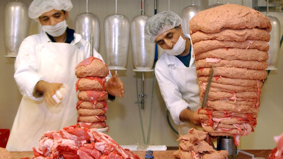 Mitarbeiter einer Frankfurter Dönerfabrik verarbeiten Fleisch zu einem Dönerspieß Mitarbeiter einer Frankfurter Dönerfabrik verarbeiten Fleisch zu einem Dönerspieß