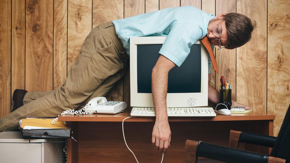Der Büroalltag kann für den Körper ziemlich anstrengend sein. Mann liegt müde auf einem Computer
