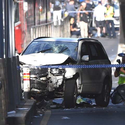 Ein Polizist fotografiert das Fahrzeug, mit dem ein Mann in Melbourne eine Menschenmenge gerast ist