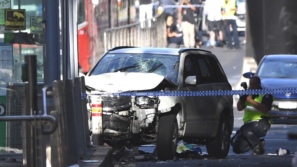 Ein Polizist fotografiert das Fahrzeug, mit dem ein Mann in Melbourne eine Menschenmenge gerast ist