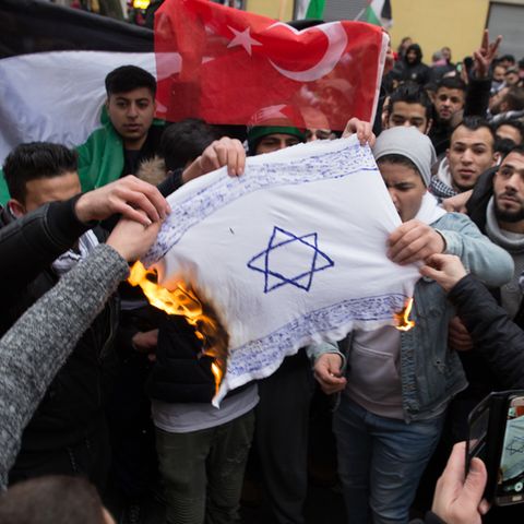 In Berlin-Neukölln zünden Demonstranten eine selbst gemachte Flagge mit Davidstern an